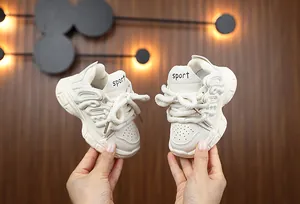 Detail of children's chunky white sneakers with sport lettering and thick laces