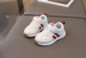 Detail view of white toddler sneakers with red side stripes and anti-slip rubber soles
