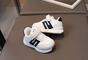 Détail de chaussures de sport enfant avec motif S noir, bande velcro et semelle antidérapante