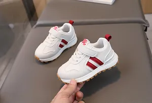 Close-up of white leather kids sneakers with red stripes and secure velcro strap