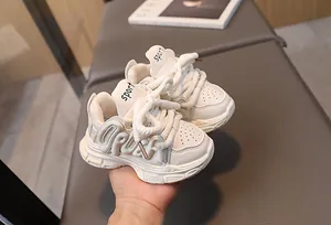 Detailed macro view of children's chunky sneakers featuring 3D letter relief and thick laces