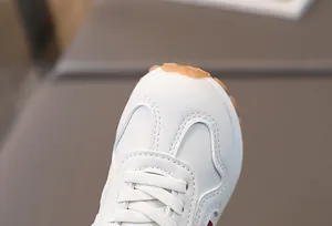 Detailed view of white leather baby shoes featuring lace-up design and gum rubber sole
