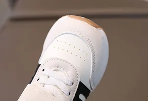 Gros plan de chaussures de sport pour enfants montrant le cuir perforé et les coutures