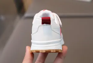 Detail view of toddler white leather sneakers featuring a non-slip brown rubber sole