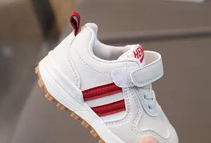 Detailed side view of white toddler sneakers featuring red stripes and non-slip rubber soles