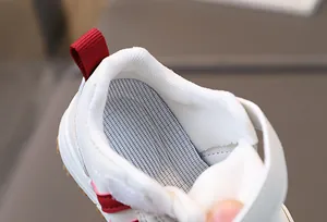 Detail of white toddler sneaker with breathable honeycomb insole and red heel pull tab