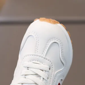 White leather baby walking shoes with soft brown anti-slip rubber sole from a front view