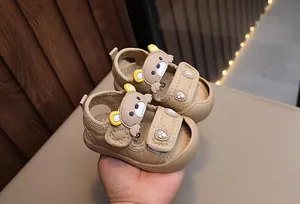 Detail of khaki baby sandal with cute cartoon bear decoration and velcro strap closure