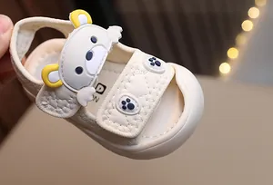 Close-up of beige baby sandals featuring 3D cartoon bear ears and velcro straps
