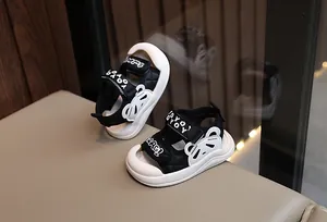 Gros plan de sandales bébé noir et blanc avec oreilles d'ours et bandes velcro