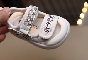 Gros plan détaillé de sandales bébé crème avec broderie SWAG et brides velcro
