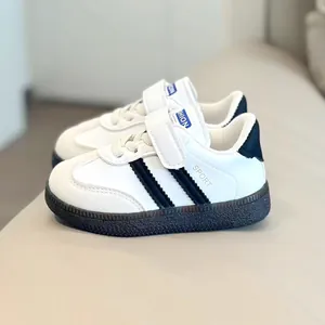 Detail view of white kids' trainers with black stripes and easy velcro strap closure