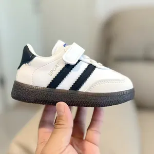 Retro kids' white sneakers with black stripes and velcro strap on brown rubber sole