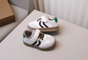 Detail of children's low-top sneakers featuring white leather and brown rubber sole
