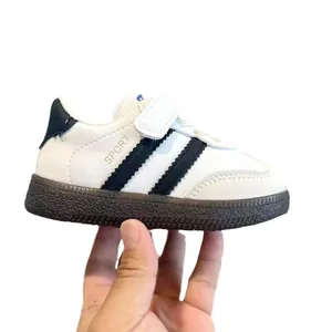 Kids minimalist white sneakers with black stripes and brown rubber sole in side view