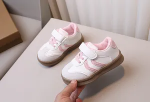Detail of pink and white kids' sneakers featuring magic tape and textured rubber sole