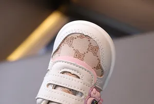 Dettaglio ravvicinato di scarpe in pelle beige per neonati con motivo a orsetto
