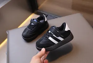 Detail of toddler black sneakers with white stripes and convenient hook-and-loop closure