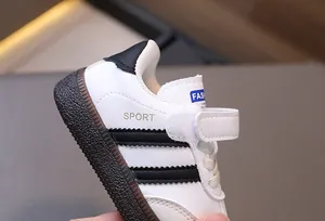 Detail of toddler retro sneakers featuring white leather, black stripes, and velcro closure
