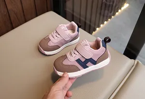 Dettaglio scarpe per bambini rosa e marroni con chiusura a velcro e lettera H