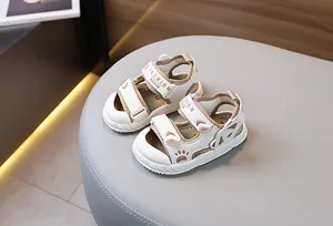Detail view of baby closed-toe sandals with velcro closure and soft soles on a soft stool
