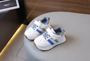 Detail view of kids sneakers featuring white leather with blue stripes and velcro closure