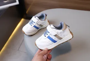 Detail of kids sneaker showing blue stripes, smiley pattern, and velcro strap with rubber sole
