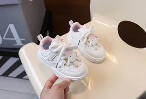 Dettaglio di scarpe da ginnastica per bambini crema con accenti rosa e pecora 3D