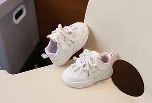 Dettaglio scarpe da ginnastica in pelle bianca per bambini con cuore rosa e ciondolo cartoon