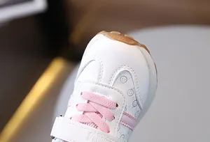 Close-up of pink and white toddler sneakers featuring a smile face and durable gum toe