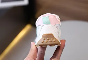 Close-up of pink and mint green kids sneakers with non-slip brown rubber outsoles