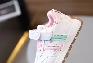 Detail view of children's sneakers with smiley prints and pink velcro straps