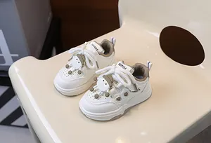Dettagli di sneakers bianche per bambini con ciondolo a cartone e cuori traforati