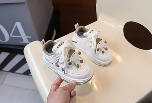 Dettaglio di sneaker in pelle bianca per bambini con pupazzo 3D e intagli a forma di cuore