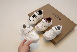 Detail of white kids sneakers with hook-and-loop straps and 1987 embroidery detail