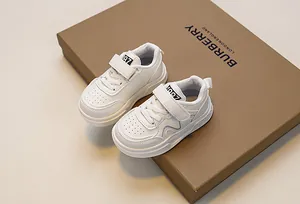 Detail of white kids sneakers with hook-and-loop closure and 1987 tongue label
