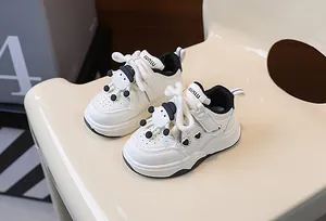Dettaglio di sneaker per neonati con ciondoli a cartone e design in pelle bianco e nero