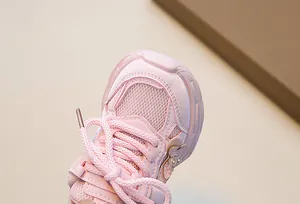 Close-up of pink girls' sneaker featuring mesh material and pearl bow decoration