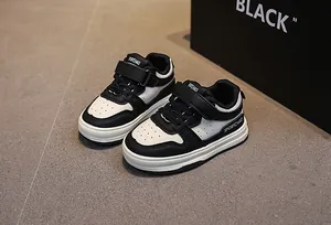 Detail of kids white leather sneakers with black accents and Velcro closure straps