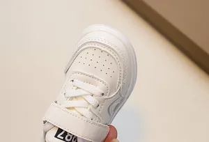 Detail of children's white sneakers showing breathable toe holes and double stitching