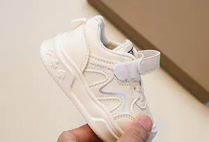 Detail of beige kids sneaker showing SPORT lettering and embossed patterns on sole