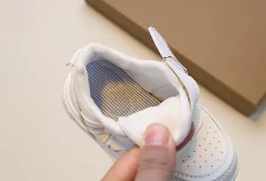Detail of children's white sneakers showing breathable mesh lining and textured insole