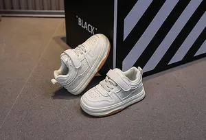 Detailed side view of off-white kids sneakers with velcro straps and rubber sole