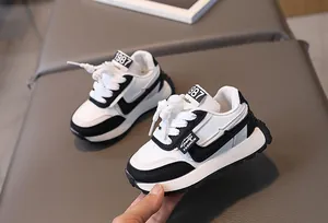 Close-up of black and white kids sneakers featuring synthetic leather and 1987 label