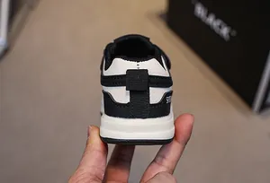 Close-up of the heel on black and white toddler sneakers featuring SPORT text detail