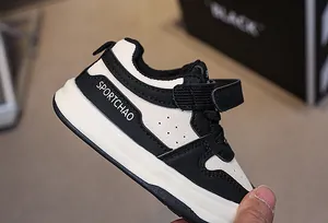 Detailed close-up of toddler sport shoes with black and white synthetic leather and velcro strap