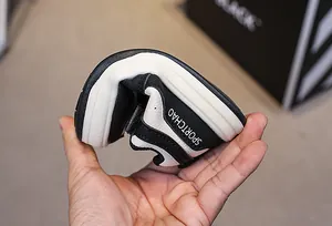 Close-up of the highly flexible white sole of a black children's sneaker being bent