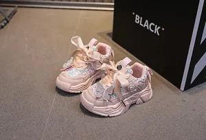 Detail of pink sequin girls sneakers featuring diamond butterfly knot and silk ribbons