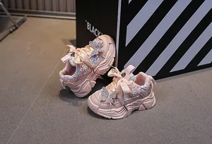Detail of pink girls sneakers featuring sequined butterfly patch and satin bow laces
