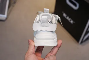 Close-up of girls' white sneakers featuring silver sequins on the heel and soft thick sole